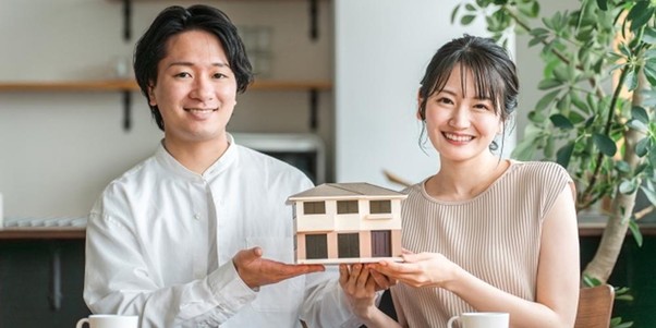 注文住宅の模型を持つ笑顔の夫婦