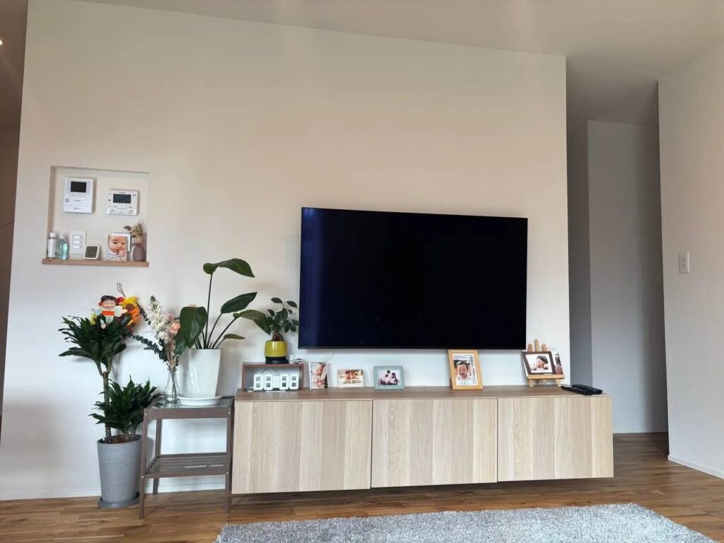 壁掛けテレビと木目のテレビボードがあるリビング