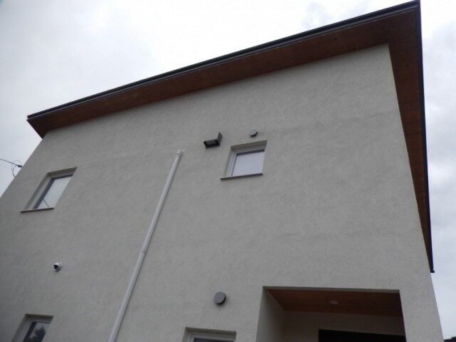 白い外壁と小さな窓があるシンプルな住宅の外観